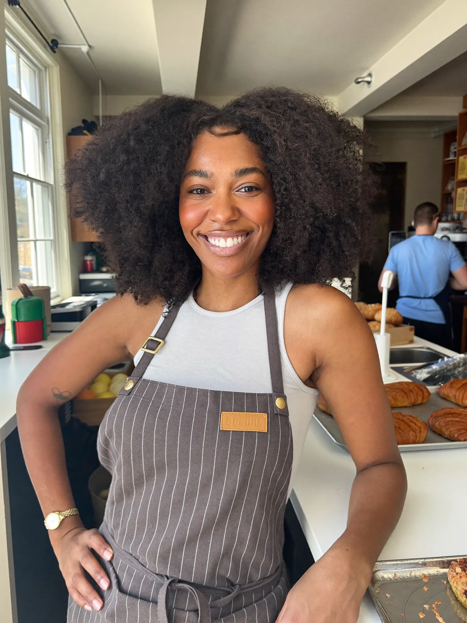 Brittany in a striped apron in her bakery kitchen with fresh croissants