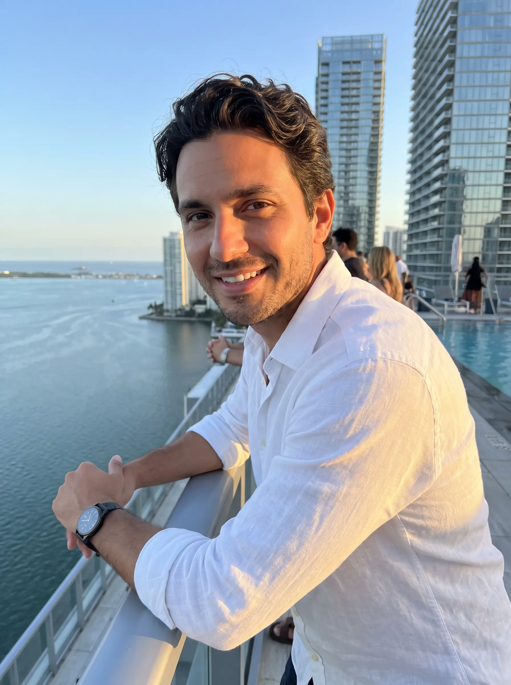 Javier in a white linen shirt on a Miami rooftop over the bay